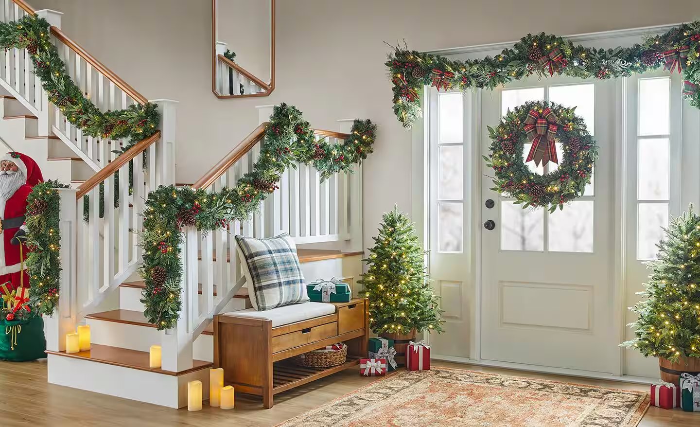 Staircase garland, wreath, and Christmas trees decorating a home entryway
